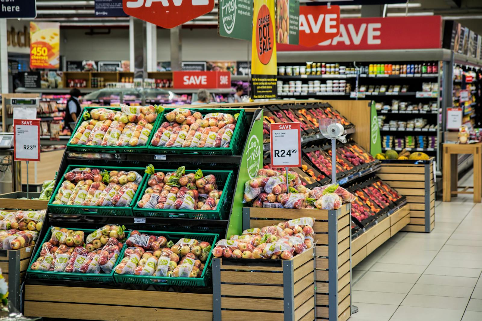 Our Services 8 Colorful produce aisle in a supermarket showcasing fresh apples with discount signage.