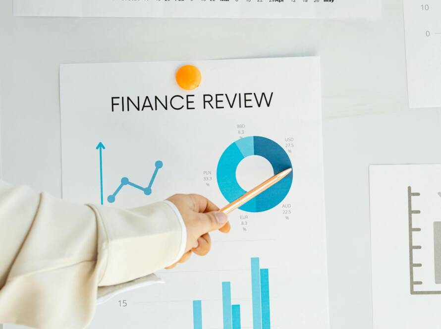 Close-up of hand pointing at finance report with charts and graphs on paper.